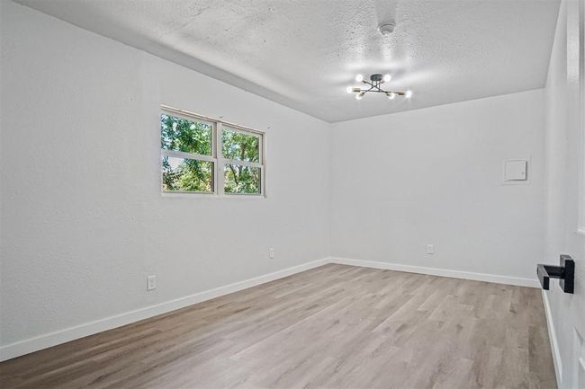 Spare room with a chandelier, light wood-style floors, and a textured ceiling | Image 4