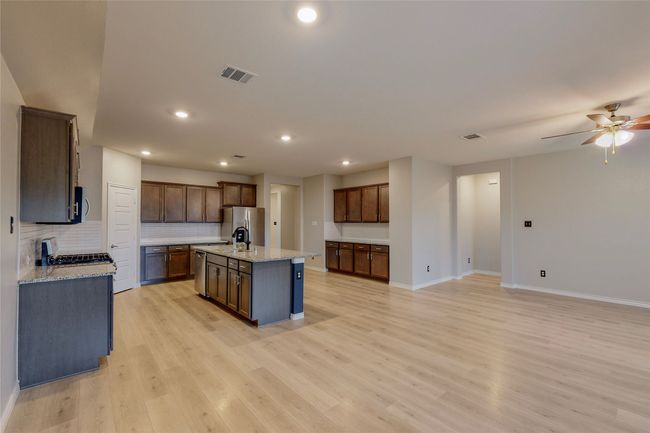 Kitchen with light wood finished floors, visible vents, backsplash, baseboards, and appliances with stainless steel finishes | Image 10