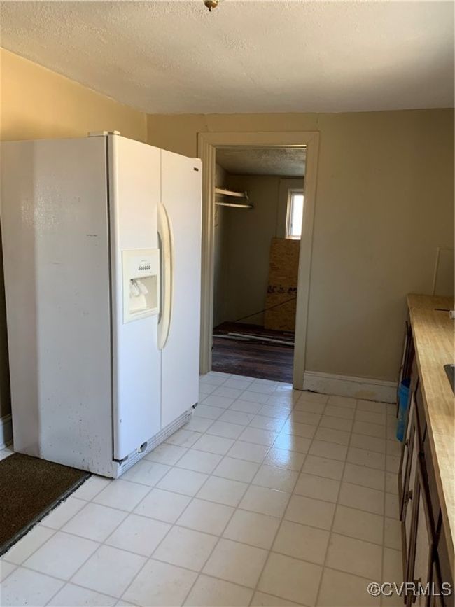 Kitchen with a textured ceiling and white fridge with ice dispenser | Image 12