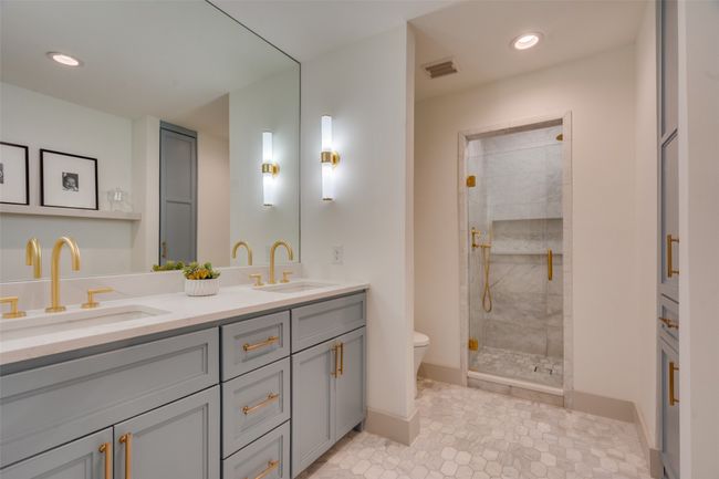 Bathroom with visible vents, a stall shower, toilet, and a sink | Image 13