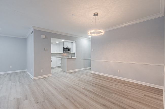 Unfurnished living room with ornamental molding, a notable chandelier, and light wood-type flooring | Image 19