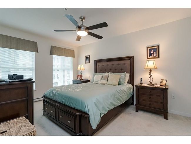 Bedroom featuring a baseboard radiator, ceiling fan, baseboards, and light carpet | Image 10