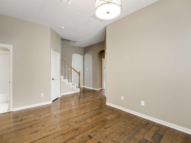 Unfurnished room featuring arched walkways, wood finished floors, and stairway | Image 28