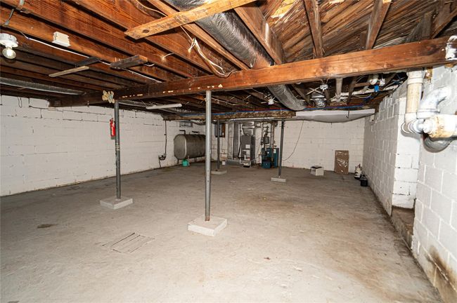 Unfinished basement with oil tank, a heating unit, and gas water heater | Image 12