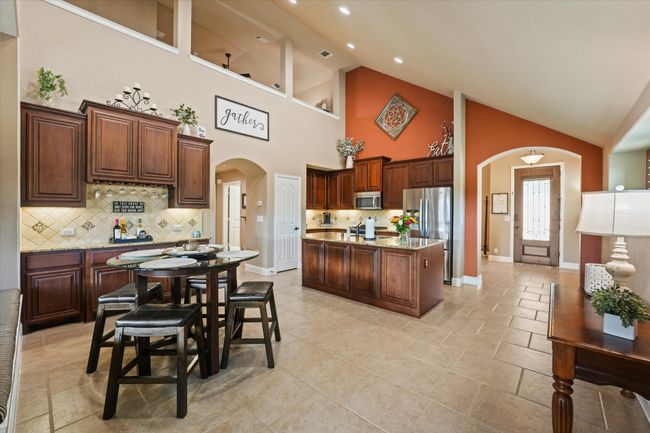 Kitchen featuring high vaulted ceiling, a center island, arched walkways, stainless steel appliances, and backsplash | Image 17
