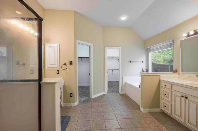 Full bathroom with a sink, two vanities, a bath, vaulted ceiling, and a walk in closet | Image 8