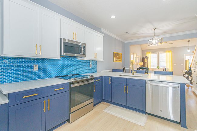 Kitchen featuring sink, appliances with stainless steel finishes, hanging light fixtures, decorative backsplash, and kitchen peninsula | Image 11