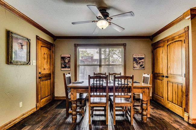 Dining room with dark wood finished floors, a textured ceiling, ornamental molding, and ceiling fan | Image 10