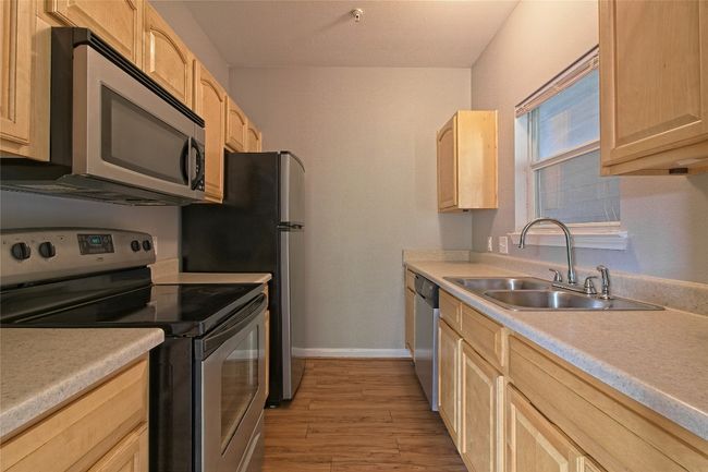 Kitchen featuring appliances with stainless steel finishes, light brown cabinetry, light wood-style floors, and light countertops | Image 18