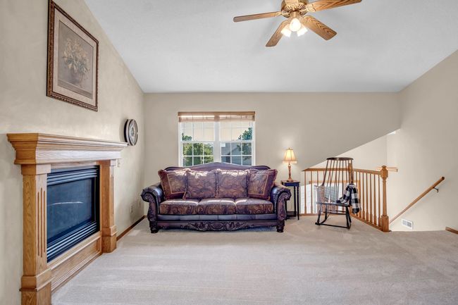 Carpeted living area with ceiling fan and a glass covered fireplace | Image 4