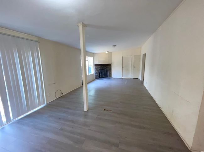 Unfurnished living room featuring dark wood-type flooring and a brick fireplace | Image 8