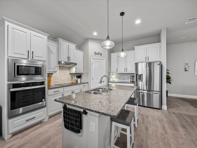 Kitchen with stainless steel appliances, decorative backsplash, an island with sink, white cabinetry, and recessed lighting | Image 7
