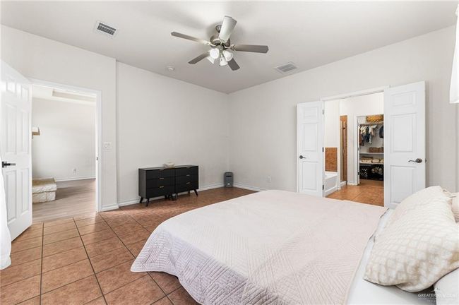 Bedroom with light tile patterned flooring, a spacious closet, a ceiling fan, and a closet | Image 10