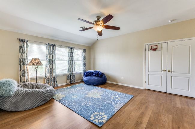 Sitting room with a ceiling fan, wood finished floors, baseboards, and vaulted ceiling | Image 22