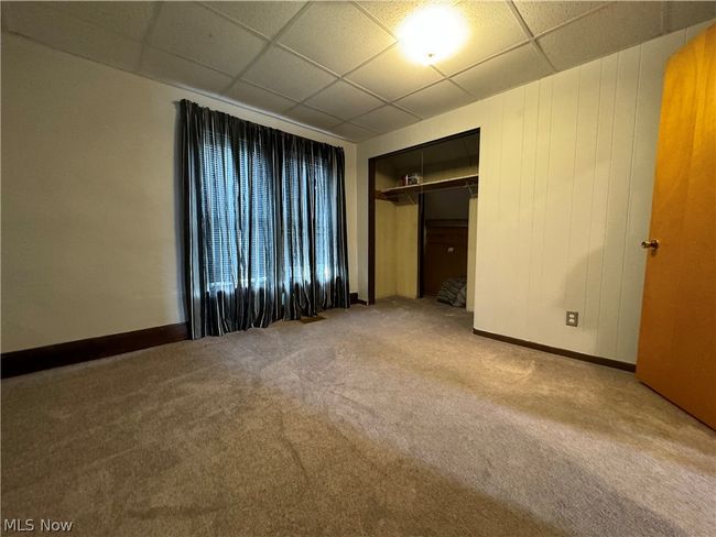 Unfurnished bedroom with carpet flooring, a closet, and a paneled ceiling | Image 21