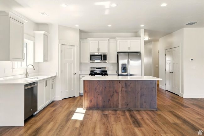 Kitchen with stainless steel appliances, a center island, dark wood-type flooring, white cabinets, and recessed lighting | Image 10