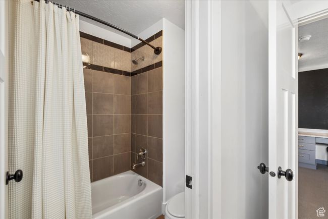 Bathroom with toilet and shower / bathtub combination with curtain | Image 38