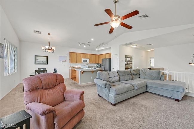 Living area featuring light carpet, lofted ceiling, plenty of natural light, and a chandelier | Image 10