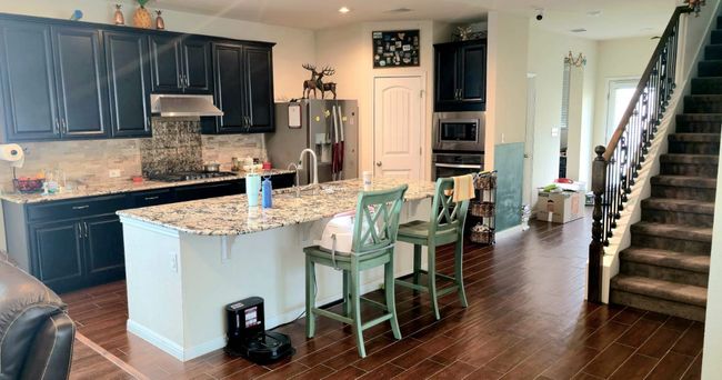 Kitchen with extractor fan, dark wood-style floors, appliances with stainless steel finishes, decorative backsplash, and a breakfast bar | Image 9
