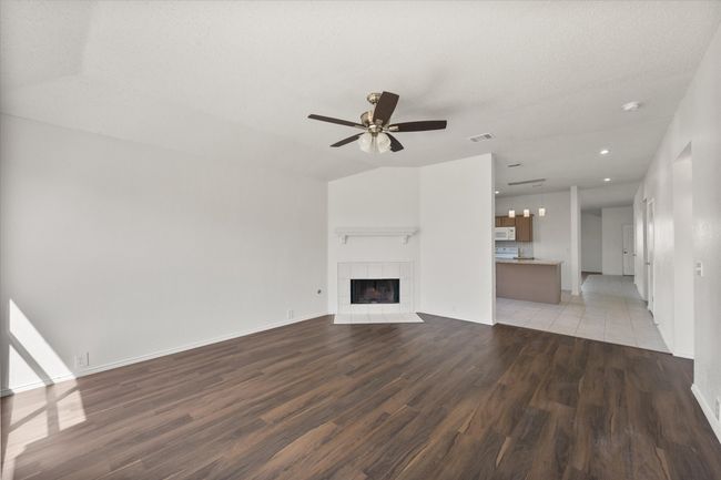 Unfurnished living room with light wood finished floors, a ceiling fan, a tiled fireplace, baseboards, and recessed lighting | Image 11
