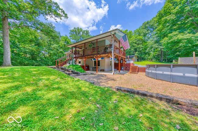 back of house with stairway, a deck, ceiling fan, a yard, and a patio area | Image 66