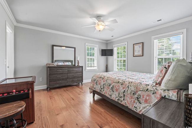 Bedroom featuring wood finished floors, crown molding, baseboards, and ceiling fan | Image 17