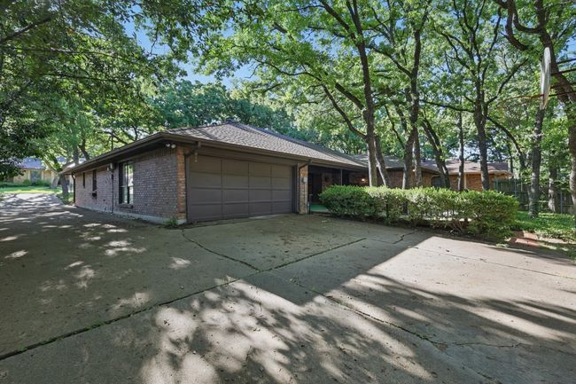 View of side of home featuring brick siding, an attached garage, concrete driveway, and fence | Image 39