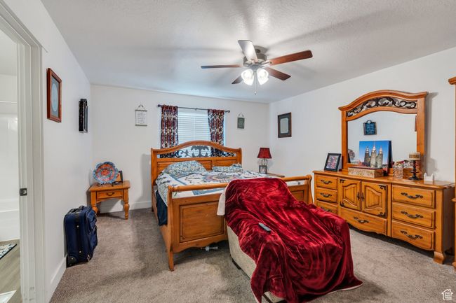Bedroom with light carpet, ceiling fan, and a textured ceiling | Image 7