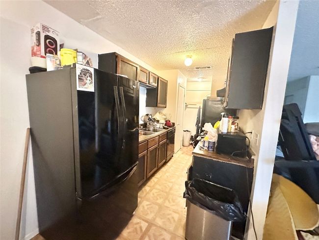Kitchen with freestanding refrigerator, a textured ceiling, and light floors | Image 7