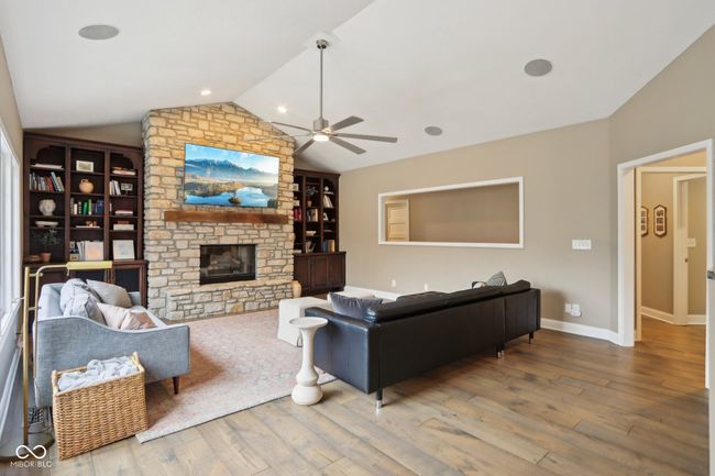 living area featuring built in features, lofted ceiling, ceiling fan, and wood finished floors | Image 21