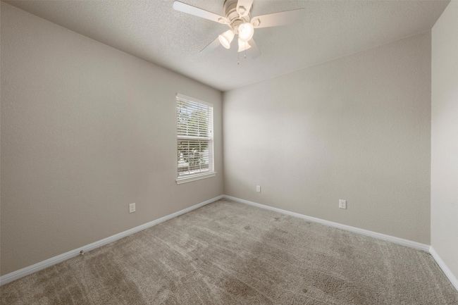 Carpeted empty room featuring ceiling fan and a textured ceiling | Image 12