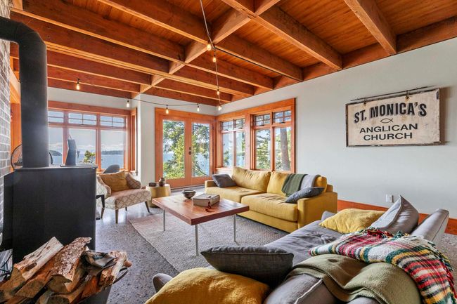 Living room featuring a wood stove, wooden ceiling with exposed beams, and speckled floor | Image 17