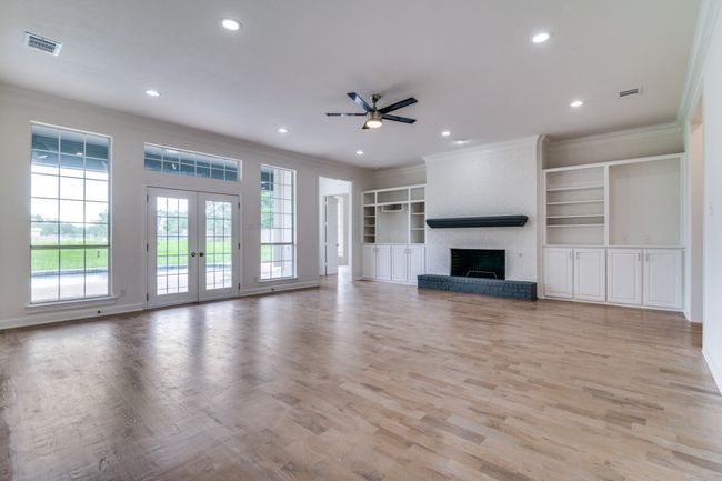 Unfurnished living room with crown molding, ceiling fan, recessed lighting, a fireplace, and french doors | Image 6