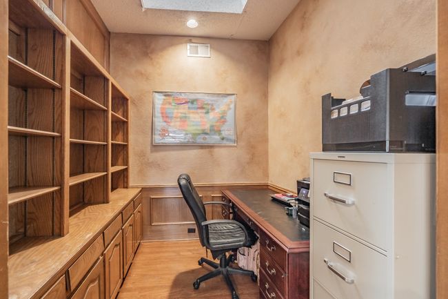 Office with light wood-style flooring, a textured wall, a wainscoted wall, and a textured ceiling | Image 4
