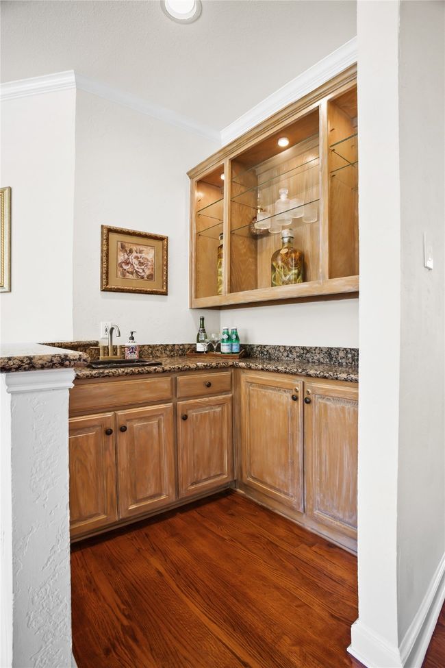 Indoor wet bar with dark wood-type flooring and crown molding | Image 14