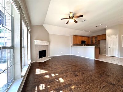 Unfurnished living room with a tile fireplace, a healthy amount of sunlight, lofted ceiling, and hardwood / wood-style floors | Image 2