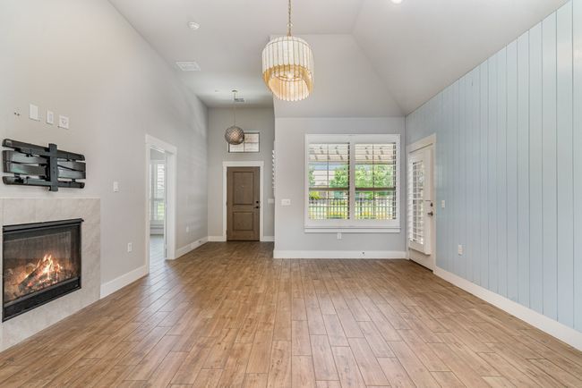 Living room featuring healthy amount of natural light, wood finished floors, a chandelier, a high end fireplace, and high vaulted ceiling | Image 7