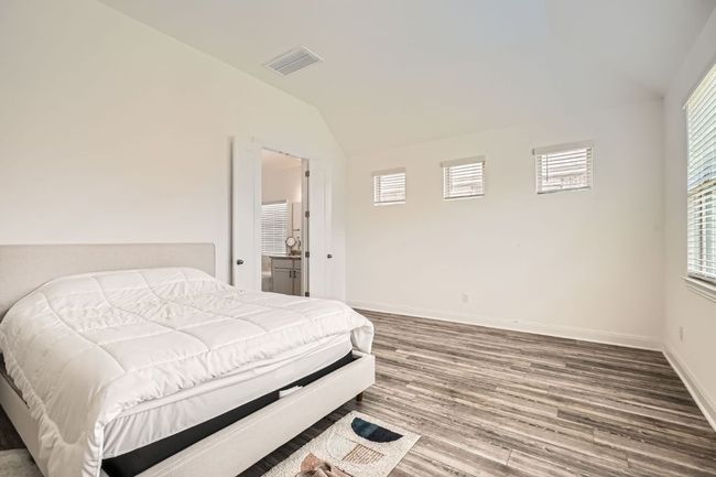 Bedroom with lofted ceiling, multiple windows, and wood finished floors | Image 16
