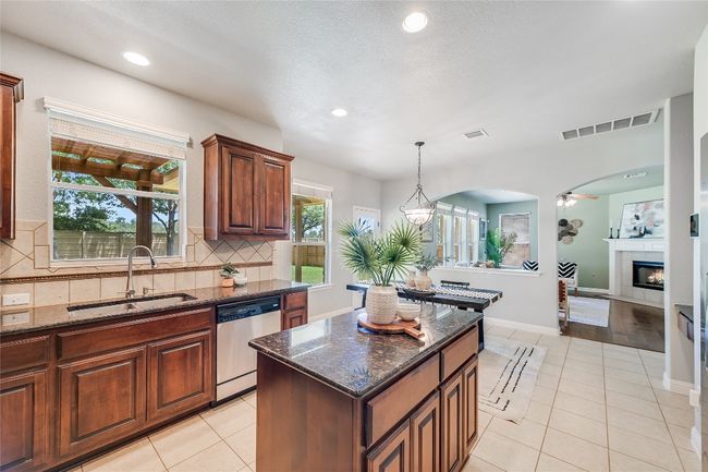 Kitchen with light tile patterned floors, stainless steel dishwasher, recessed lighting, dark stone counters, and decorative backsplash | Image 6
