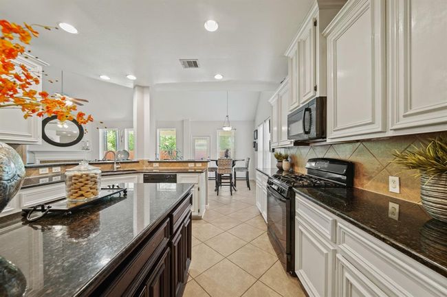 The kitchen flows effortlessly into the breakfast nook and family room, offering a connected, airy feel with views of the backyard and beyond. | Image 23