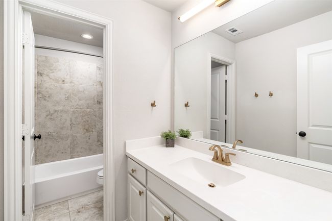 Second floor full bath with private shower and tub combination is large and features white cabinetry. | Image 30