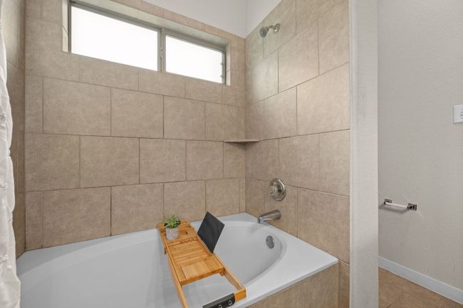 Bathroom with shower / bathtub combination with curtain, tile patterned flooring, and baseboards | Image 19