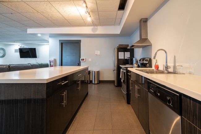 Kitchen featuring range hood, appliances with stainless steel finishes, a sink, light countertops, and rail lighting | Image 16
