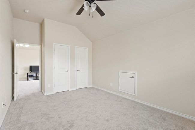 Unfurnished bedroom with carpet floors, lofted ceiling, baseboards, and ceiling fan | Image 25