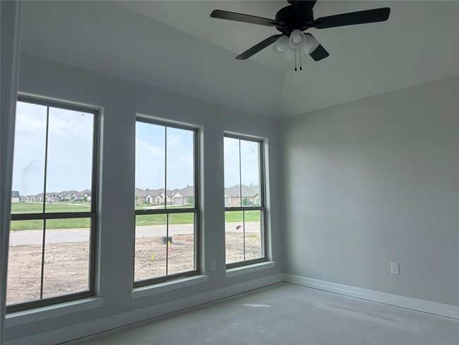 Empty room featuring concrete flooring, baseboards, a ceiling fan, and a residential view | Image 4