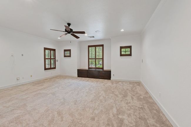 Carpeted empty room with ornamental molding, ceiling fan, plenty of natural light, and recessed lighting | Image 18