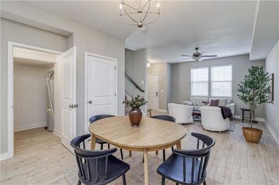 Dining area with ceiling fan with notable chandelier and light wood-type flooring | Image 2