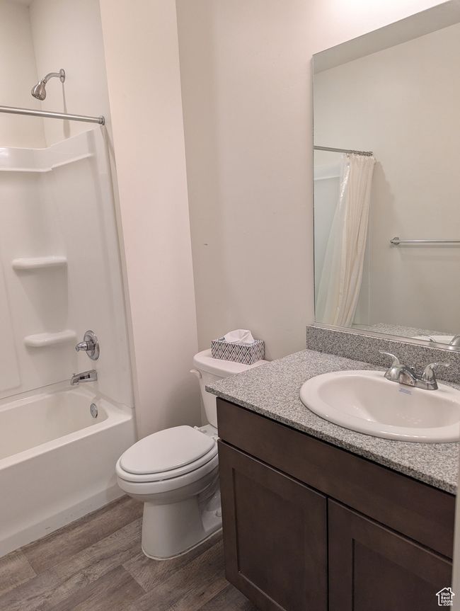 Bathroom with wood finished floors, toilet, shower / bathtub combination with curtain, and vanity | Image 21