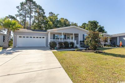 Single story home featuring a front yard, a porch, and a garage | Image 1