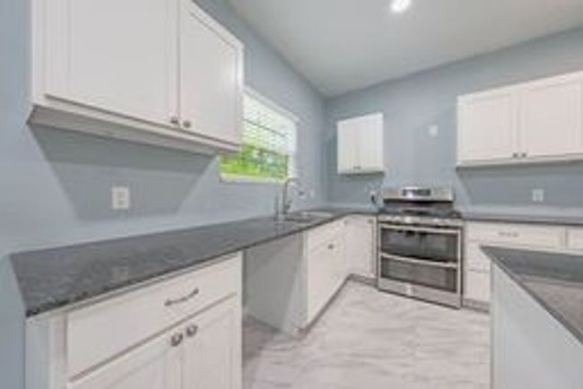 Kitchen with white cabinets, a sink, double oven range, and dark countertops | Image 15